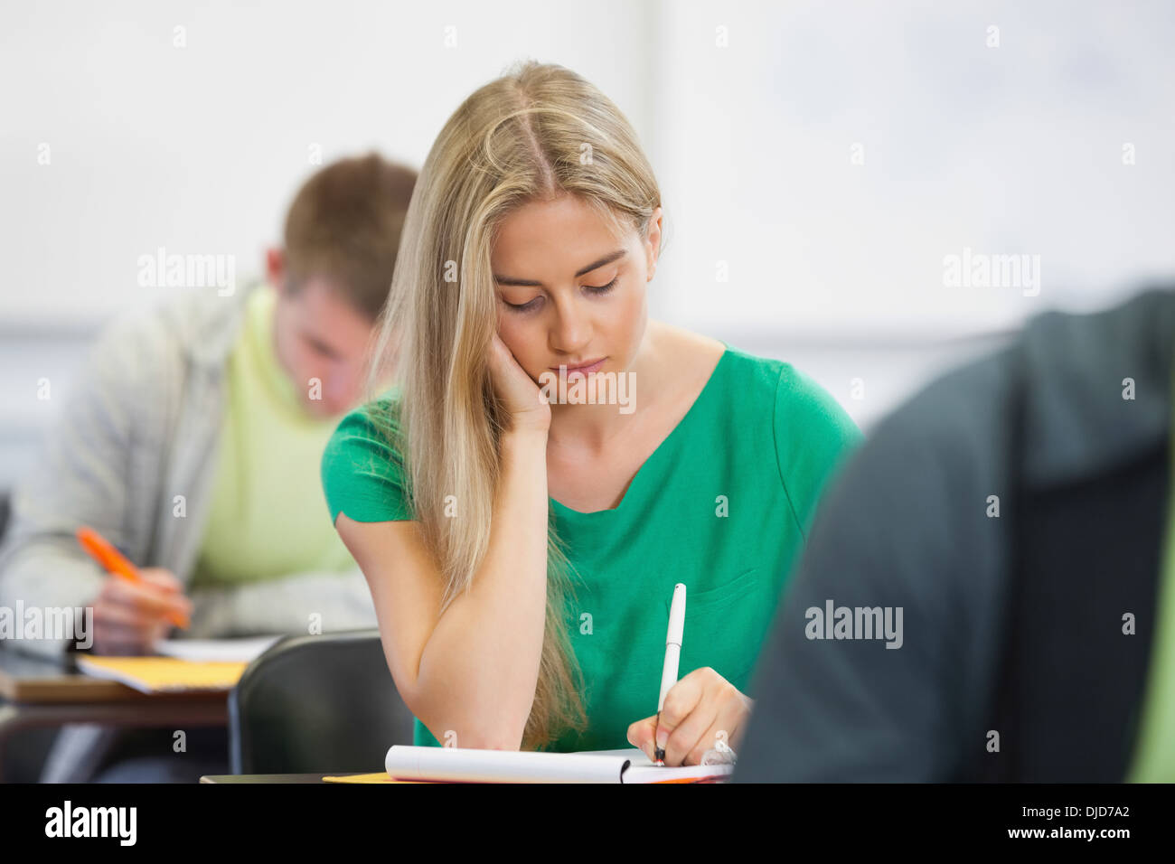 Pretty blonde student taking notes in class Stock Photo