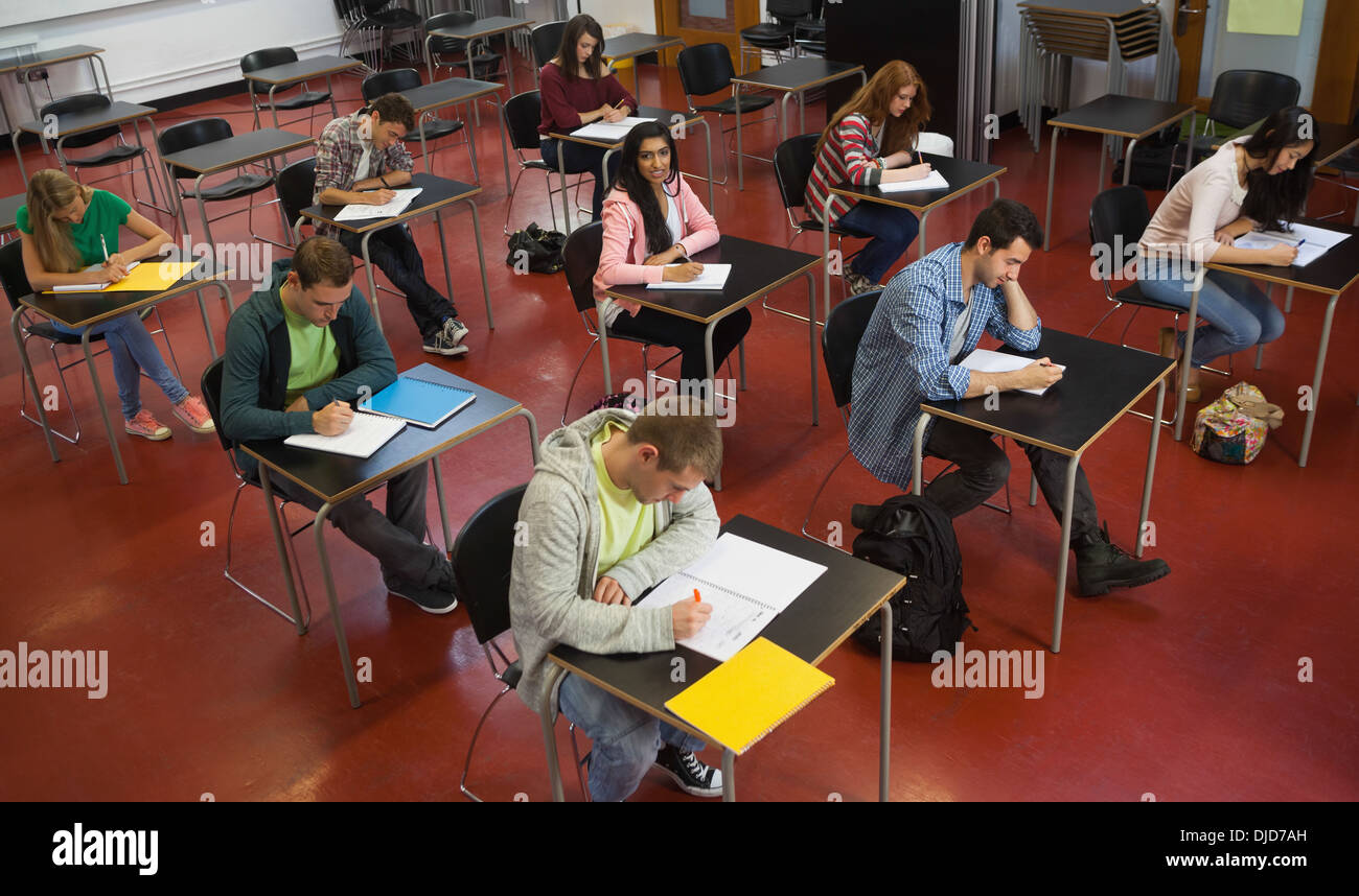 Students taking notes in class with one girl smiling up at camera Stock Photo