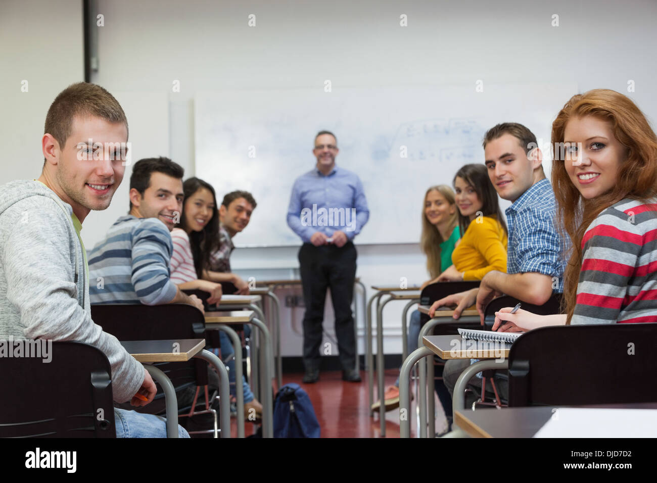 Students and lecturer smiling at camera in classroom Stock Photo