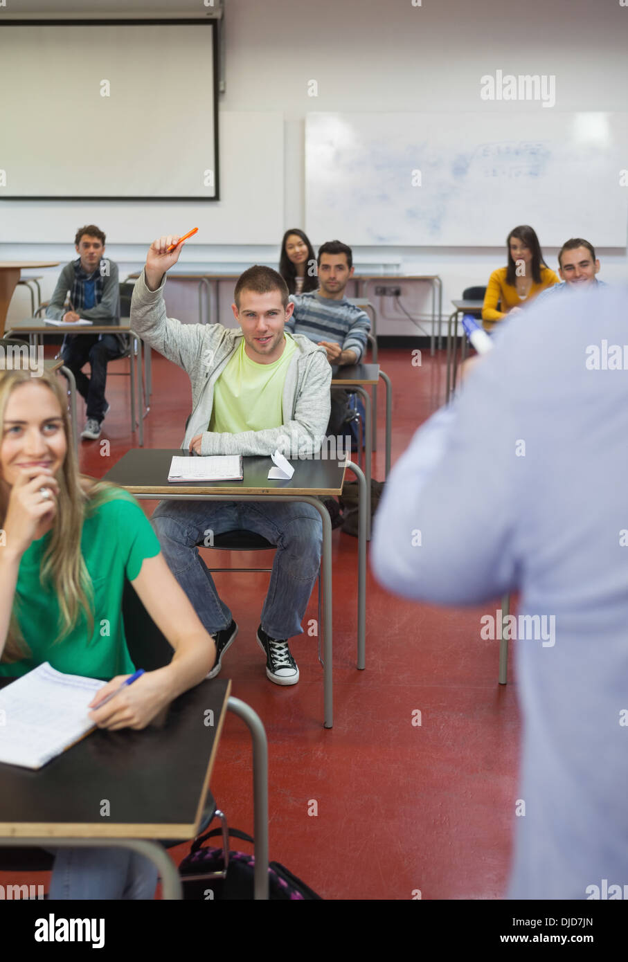 Student raising his hand to ask a question in classroom Stock Photo