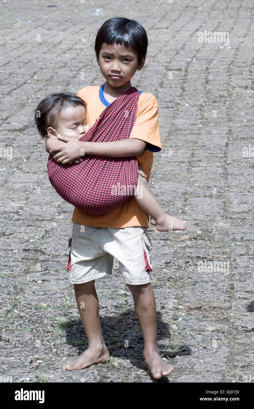 Young boy and infant brother in arms, begging on the streets of Phnom Penh Cambodia S. E. Asia Stock Photo