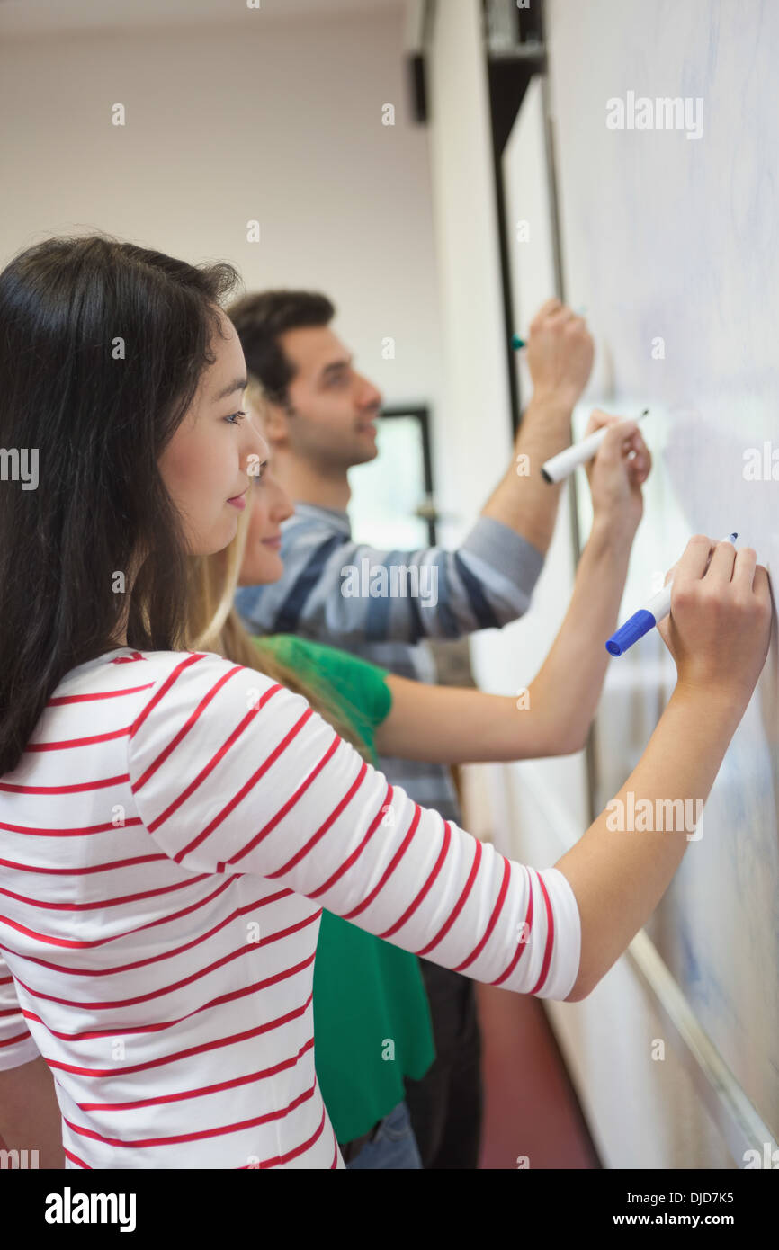 Students writing on the whiteboard together in class Stock Photo