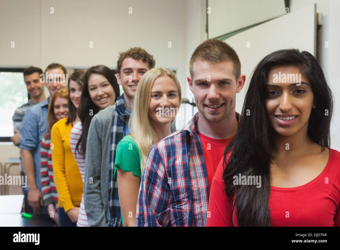 Students standing in a row in class smiling at camera Stock Photo