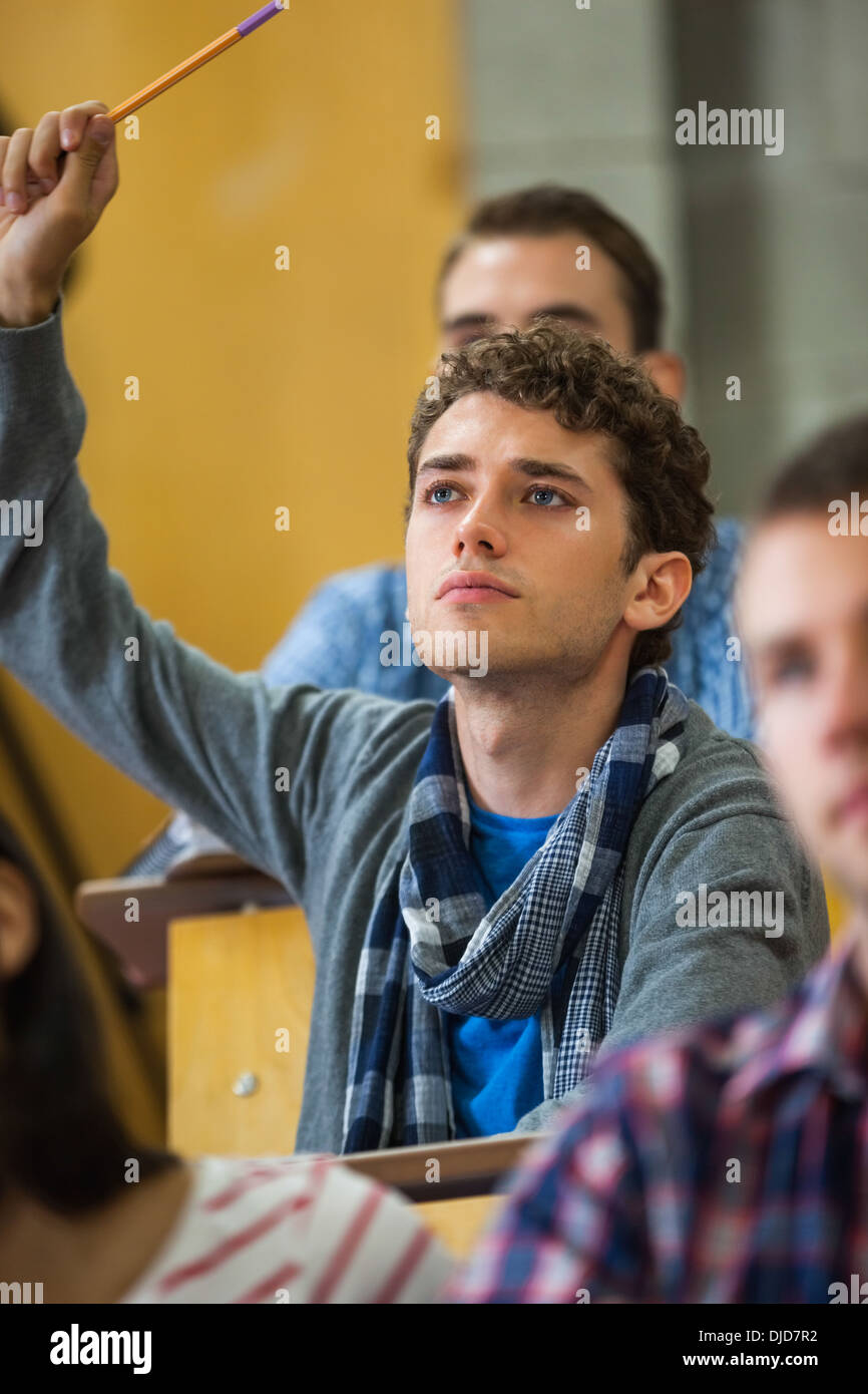 Focused student raising his hand in lecture Stock Photo