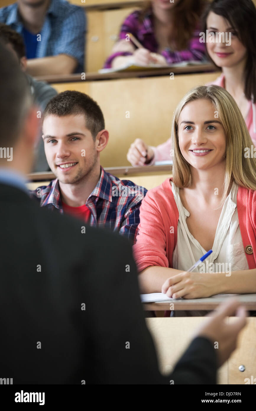 Happy students listening to teacher in lecture hall Stock Photo