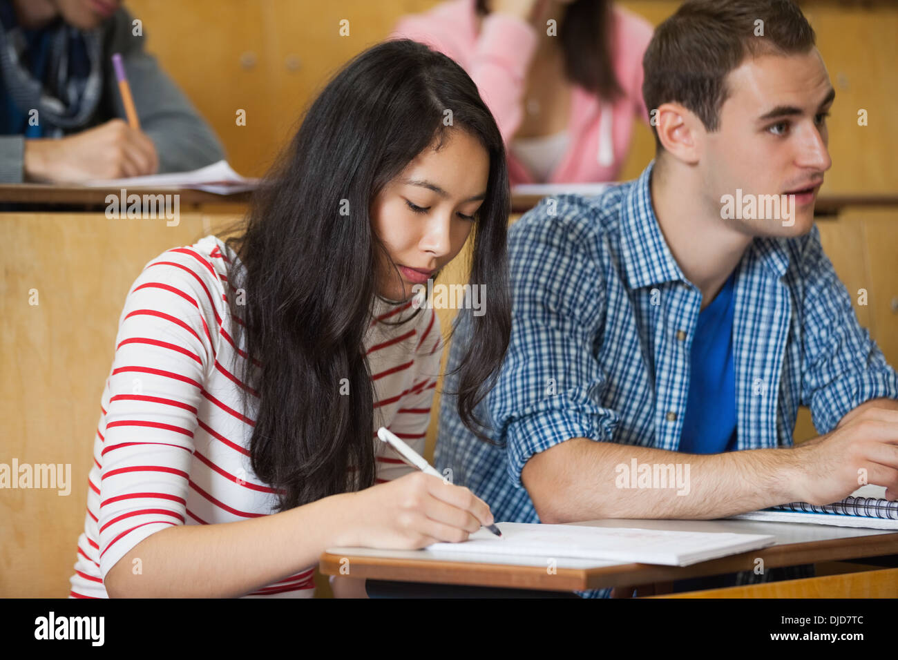 Focused students taking notes in lecture hall Stock Photo