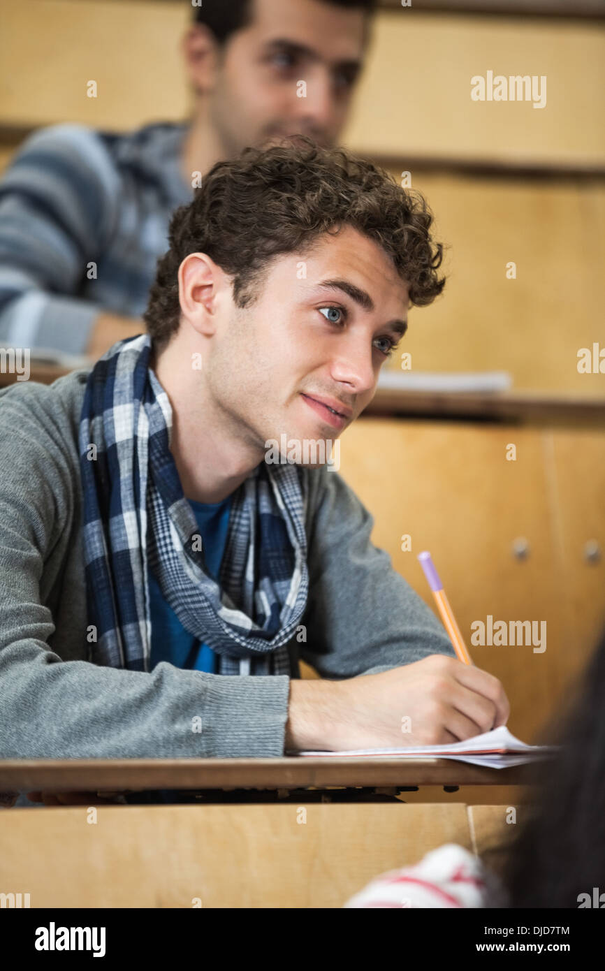 Focused student taking notes in lecture hall Stock Photo