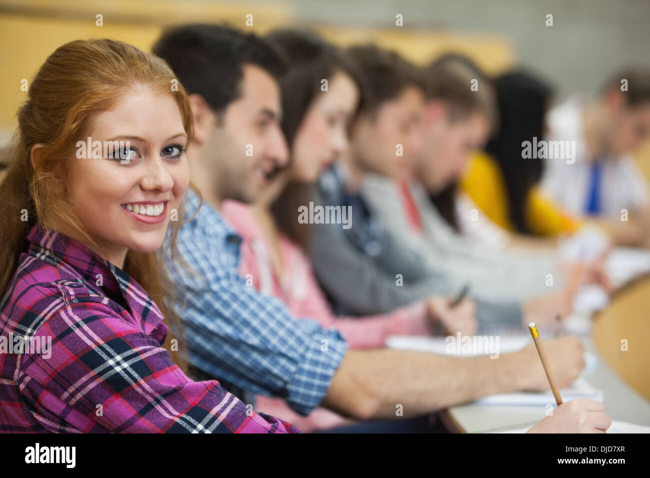 Row of students listening in a lecture hall with one smiling at camera Stock Photo