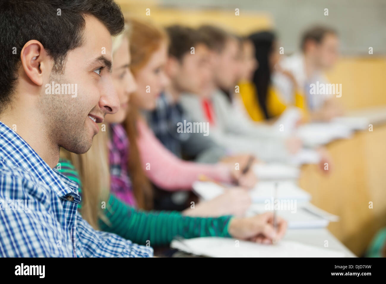 Row of smiling students listening in a lecture hall Stock Photo