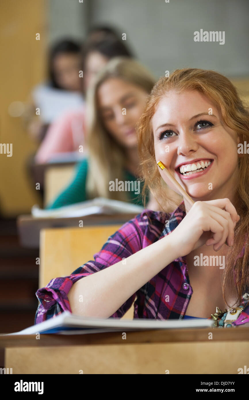 Thoughtful red head student listening in a lecture hall Stock Photo