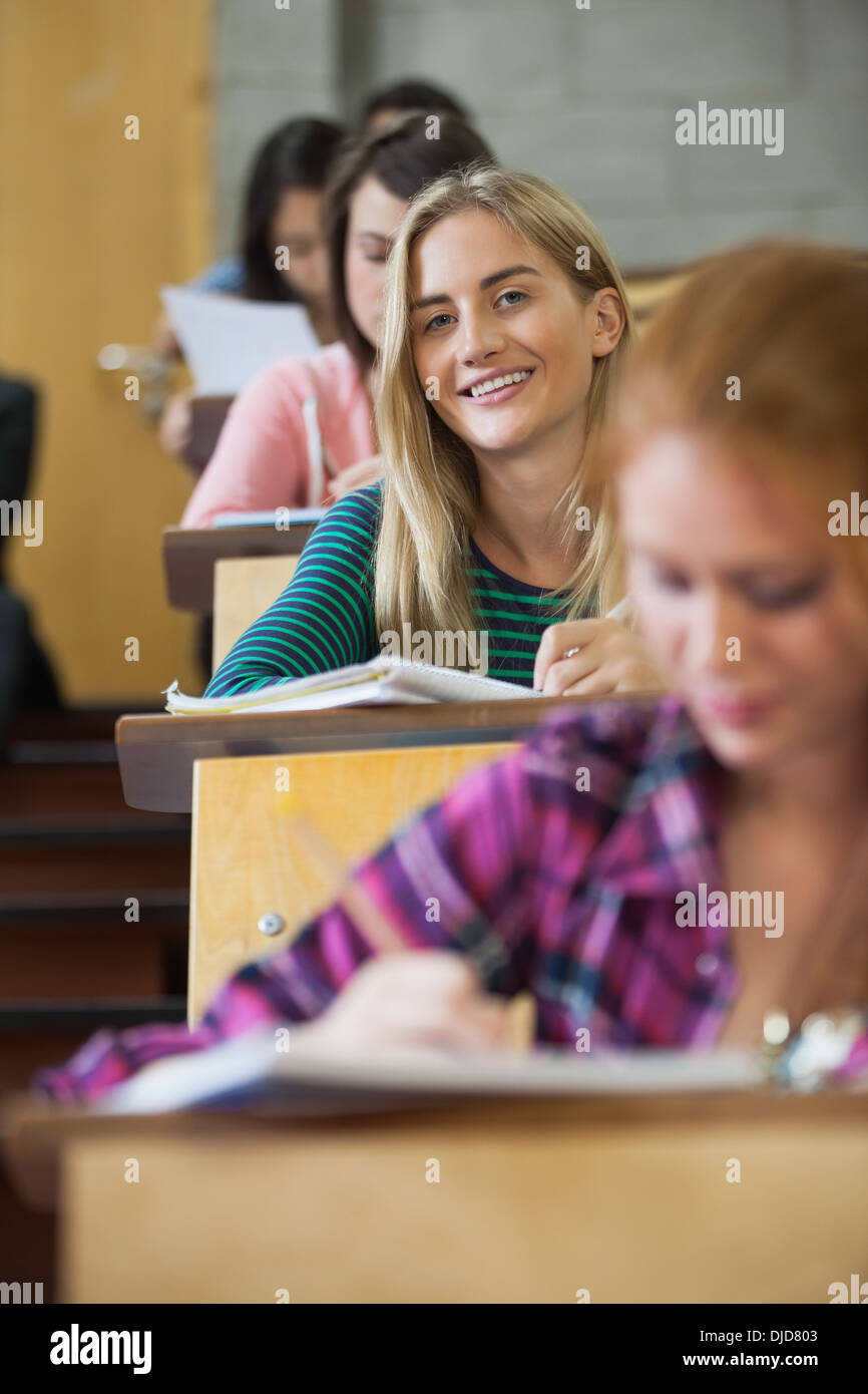 Pretty blonde student smiling at camera in a lecture hall Stock Photo