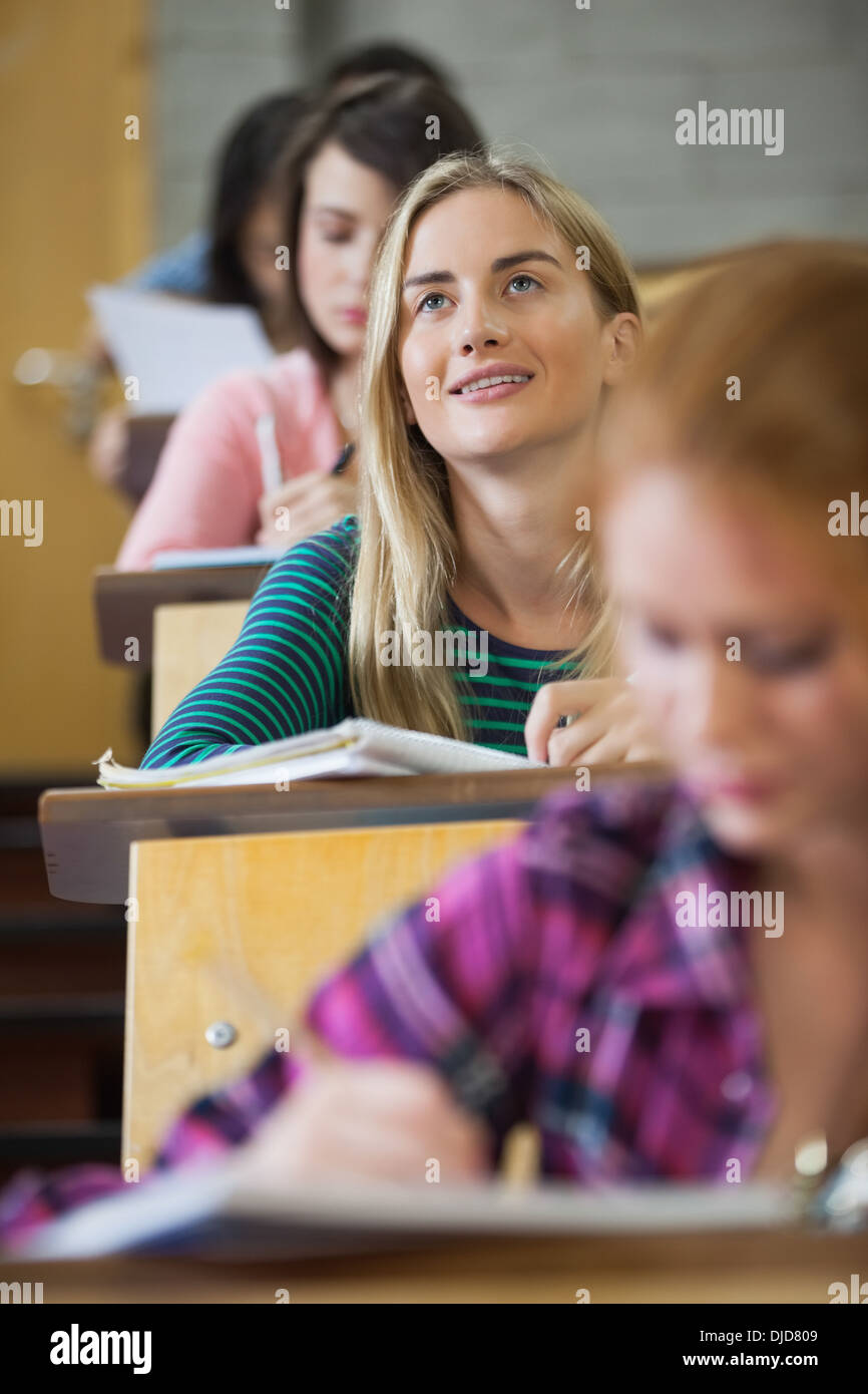 Pretty blonde student thinking in a lecture hall Stock Photo
