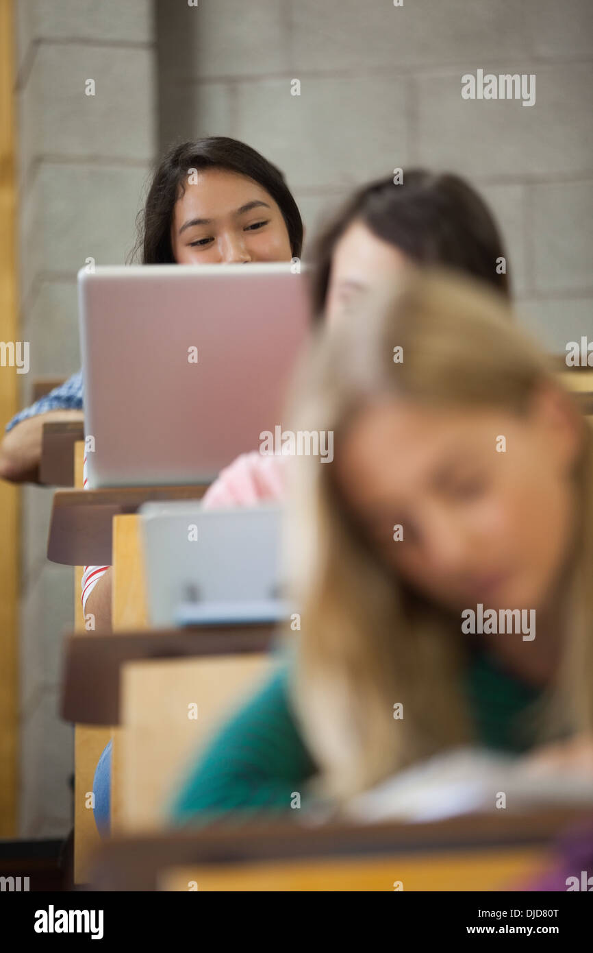 Pretty asian student using her laptop in a lecture hall Stock Photo