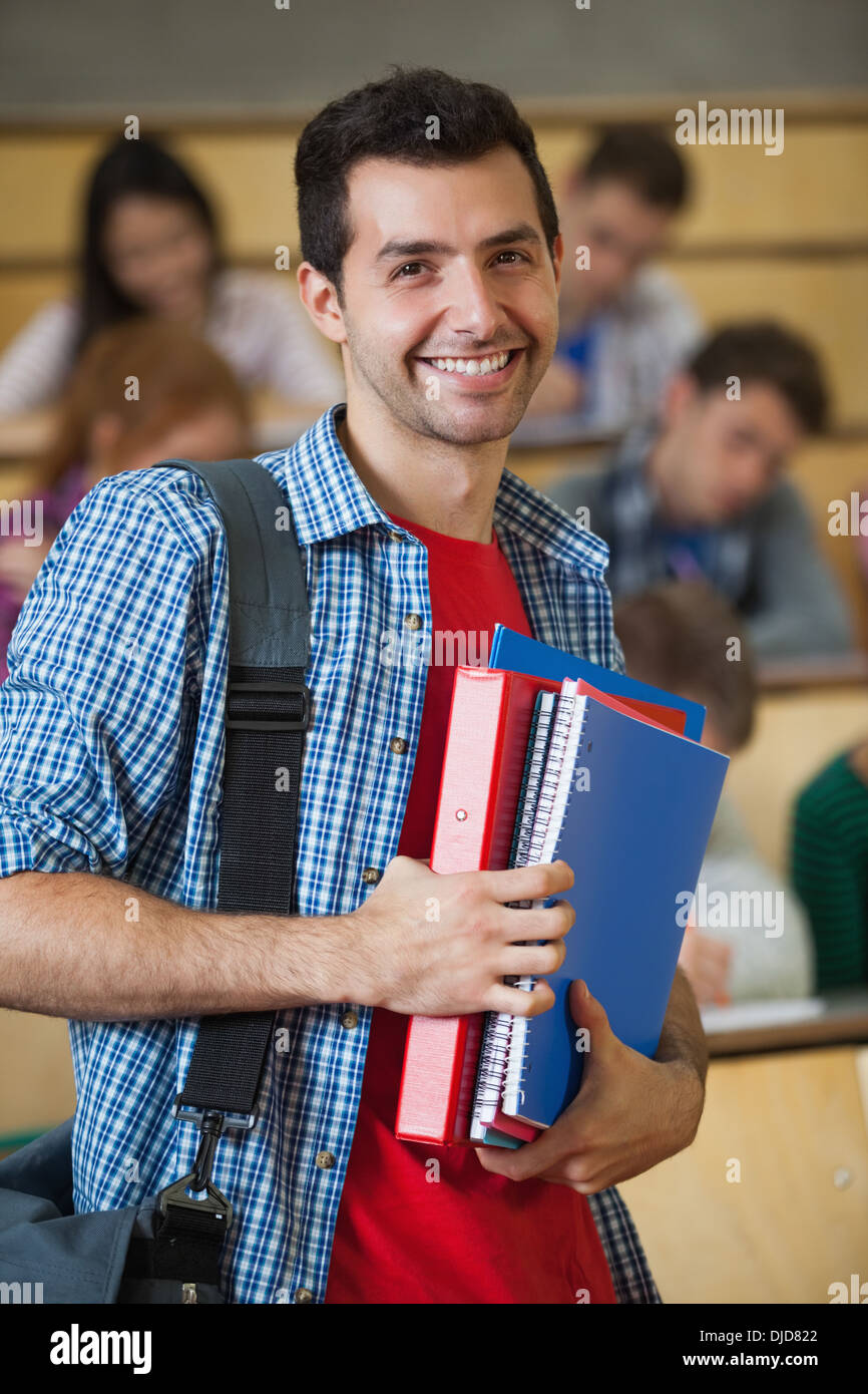 Happy student standing in front of his class in lecture hall smiling at camera Stock Photo