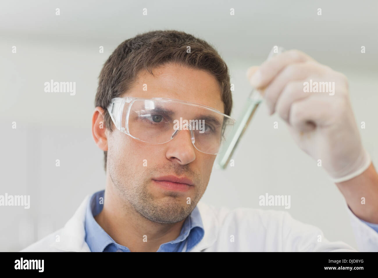 Concentrated male scientist looking at small test tube Stock Photo Alamy