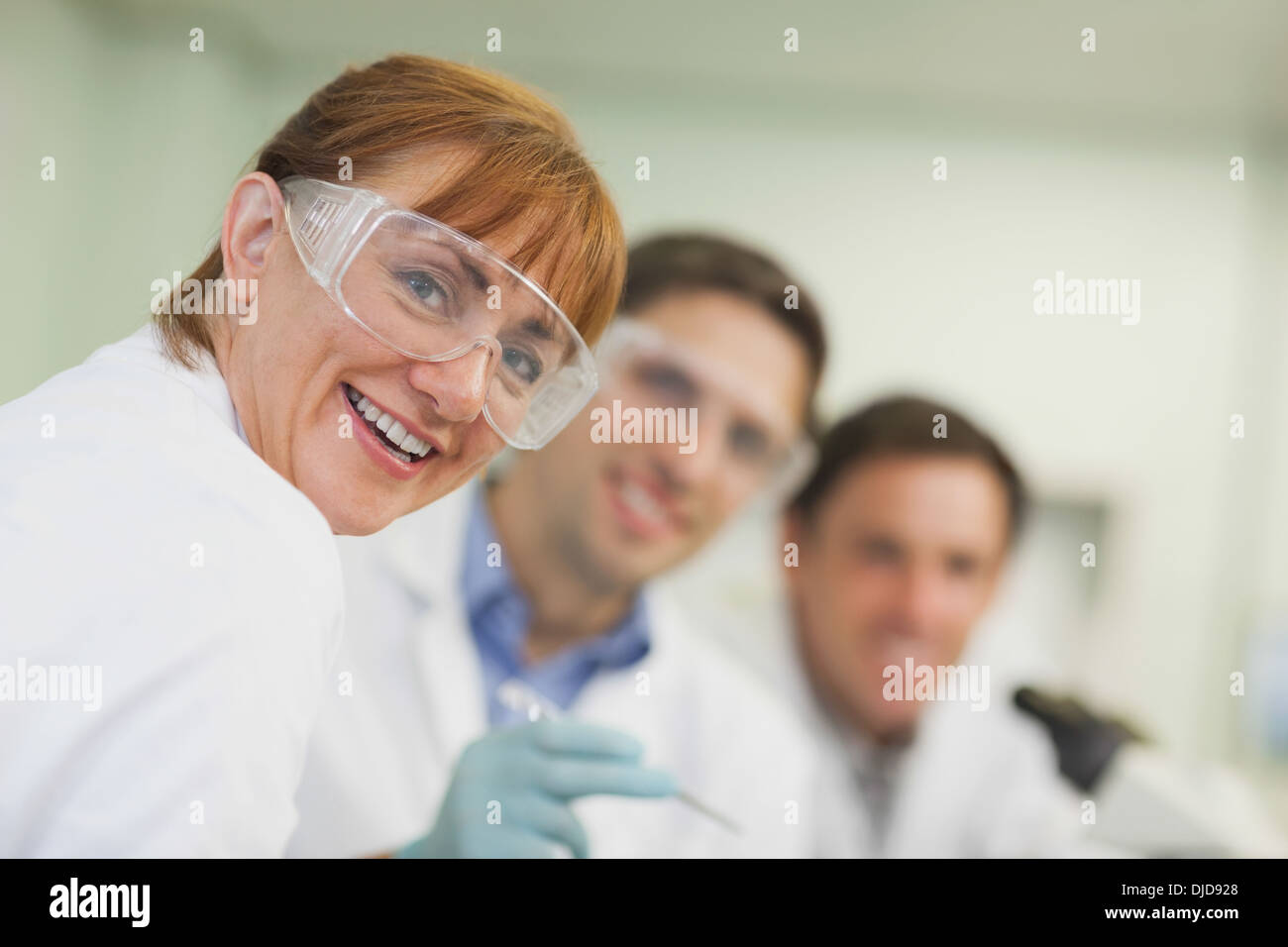 Amused female scientist standing in laboratory with her colleagues Stock Photo