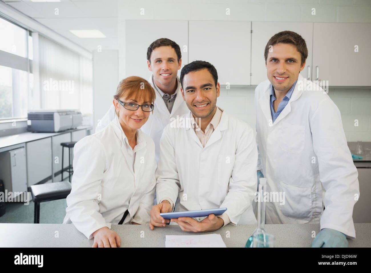 Some scientists standing behind a desk in the laboratory holding a tablet Stock Photo