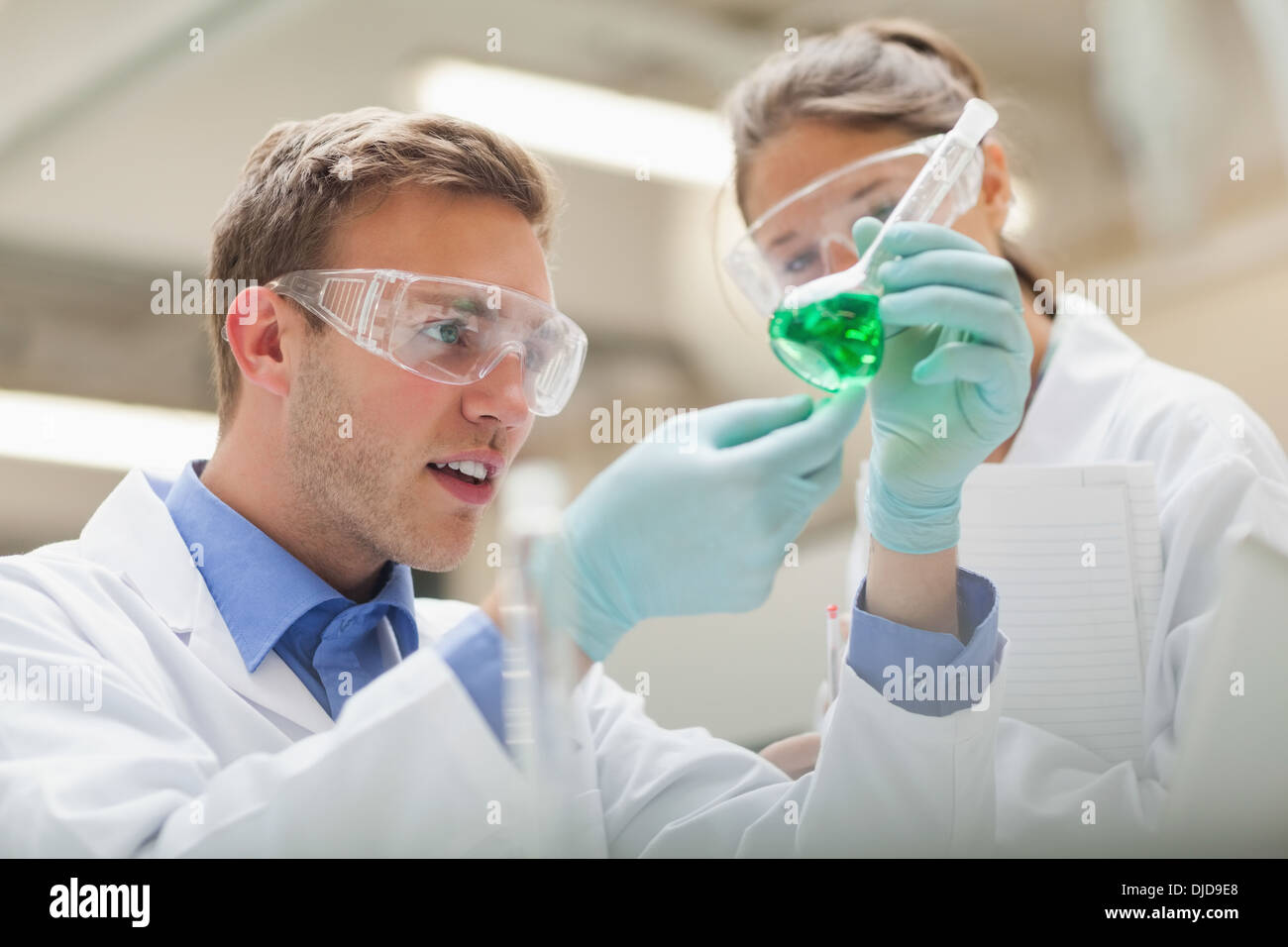 Two students looking at green liquid and taking notes Stock Photo