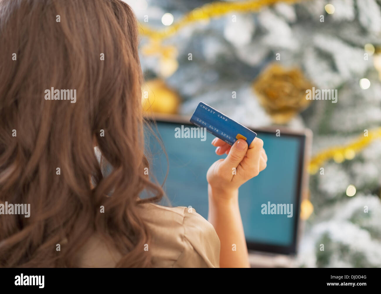 Woman making online shopping in front of christmas tree . rear view Stock Photo