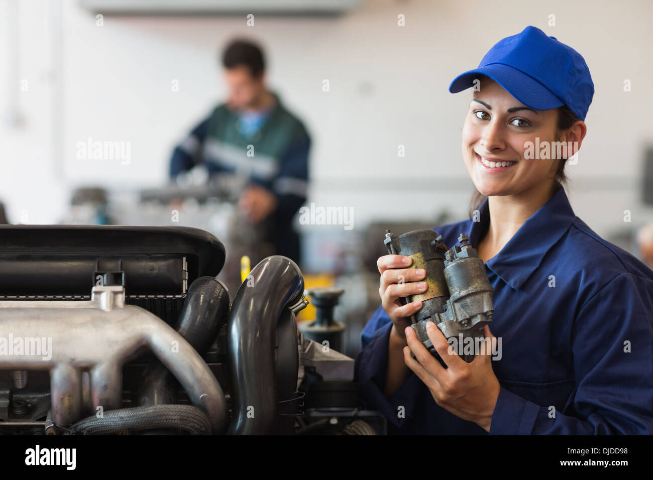 Smiling trainee showing part of a machine Stock Photo