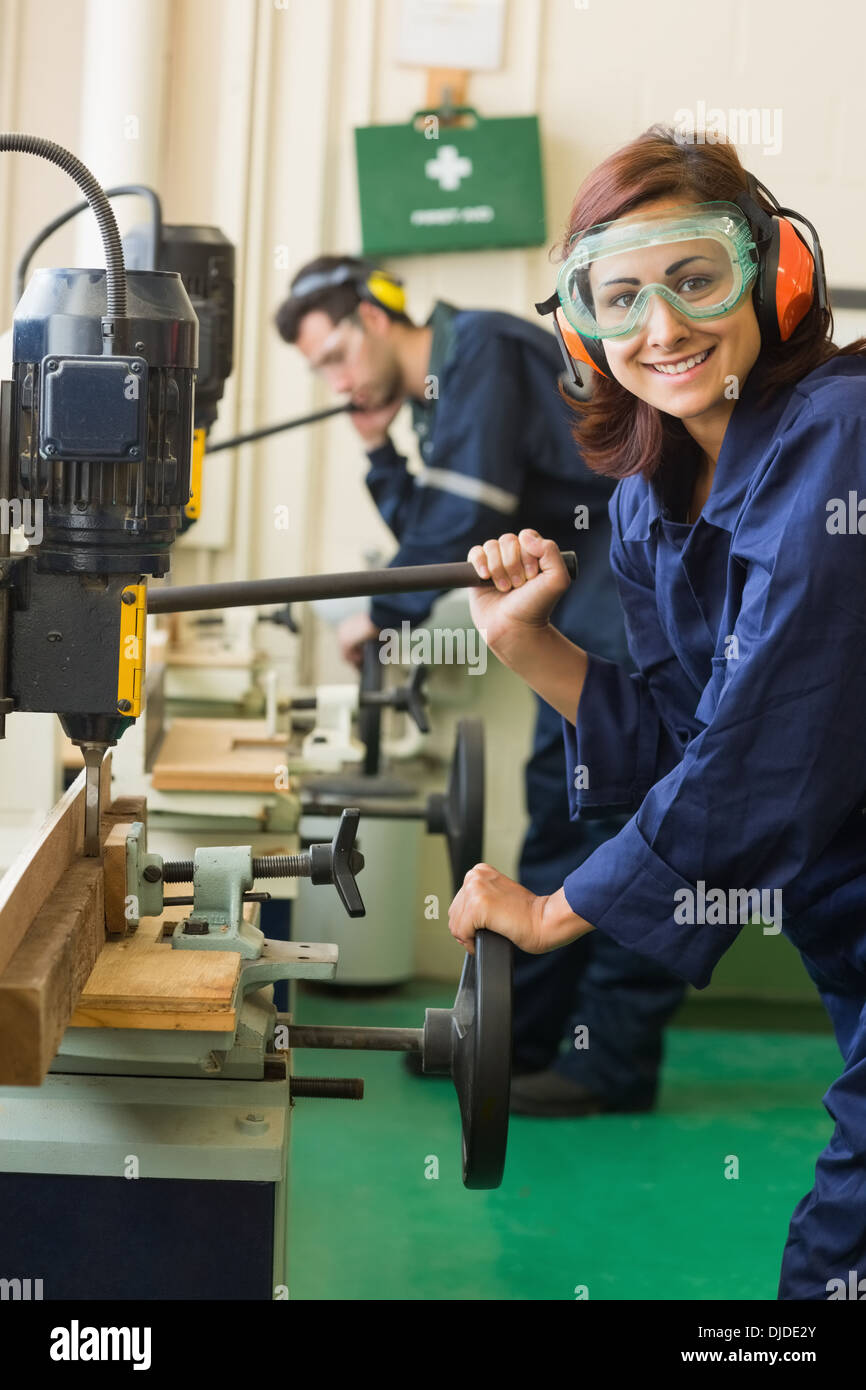 Cheerful trainee with safety glasses drilling wood Stock Photo Alamy