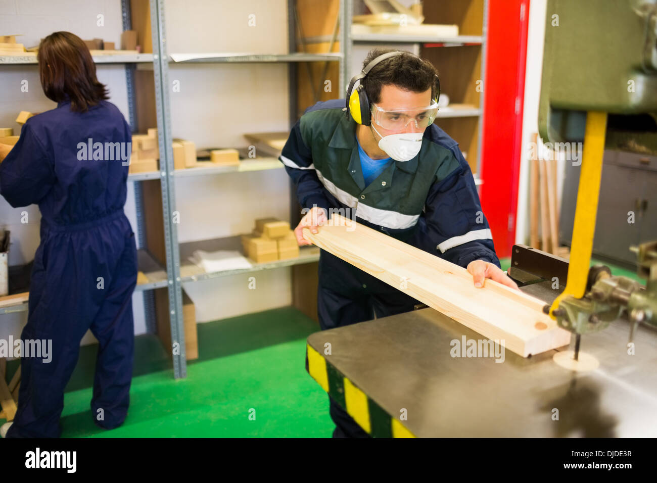 Focused craftsman wearing safety protection using saw Stock Photo