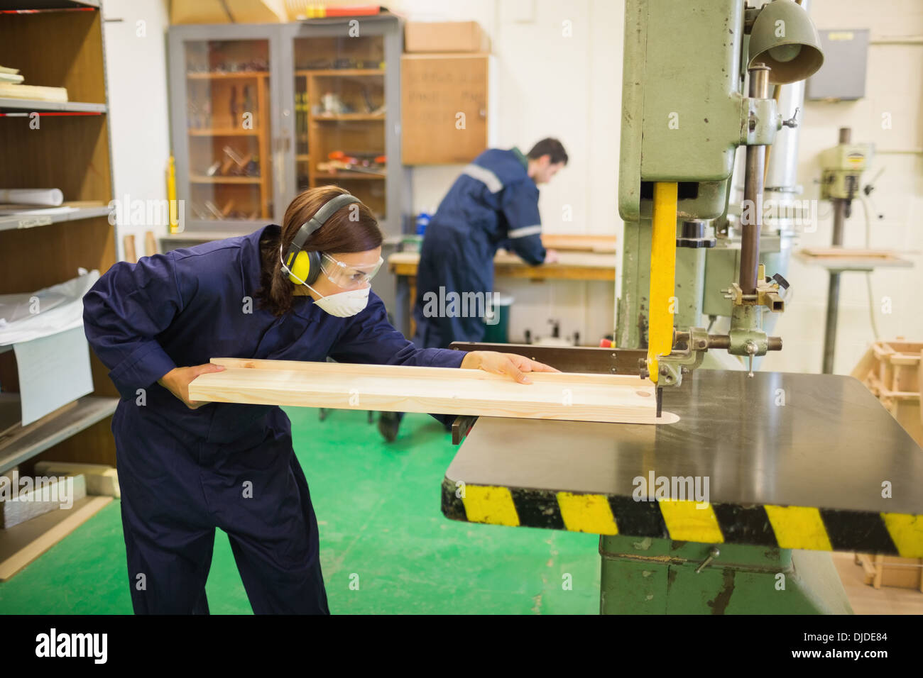Concentrating trainee wearing safety protection using a saw Stock Photo