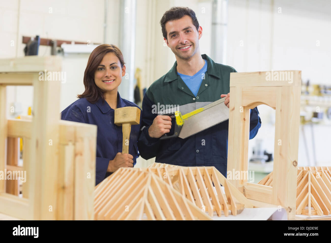 Cheerful trainee and instructor standing behind construction Stock Photo