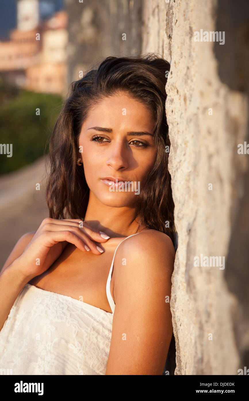 Headshot of attractive girl with dark complexion and long hair leaning against a sandstone cliff Stock Photo