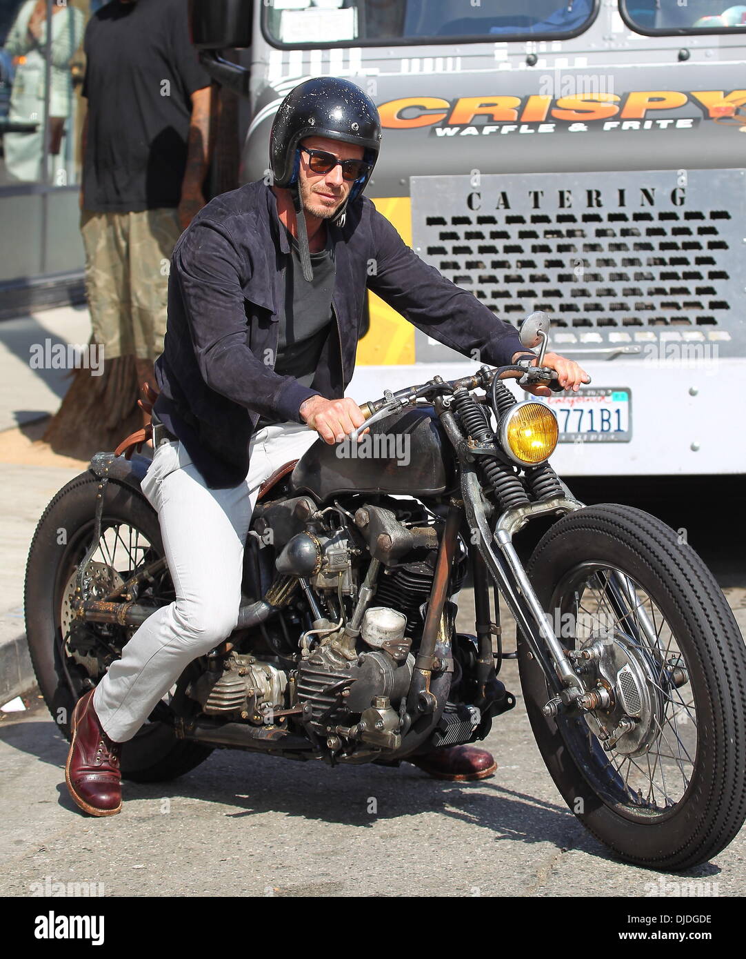 David Beckham returns to his parked Harley Davidson motorcycle