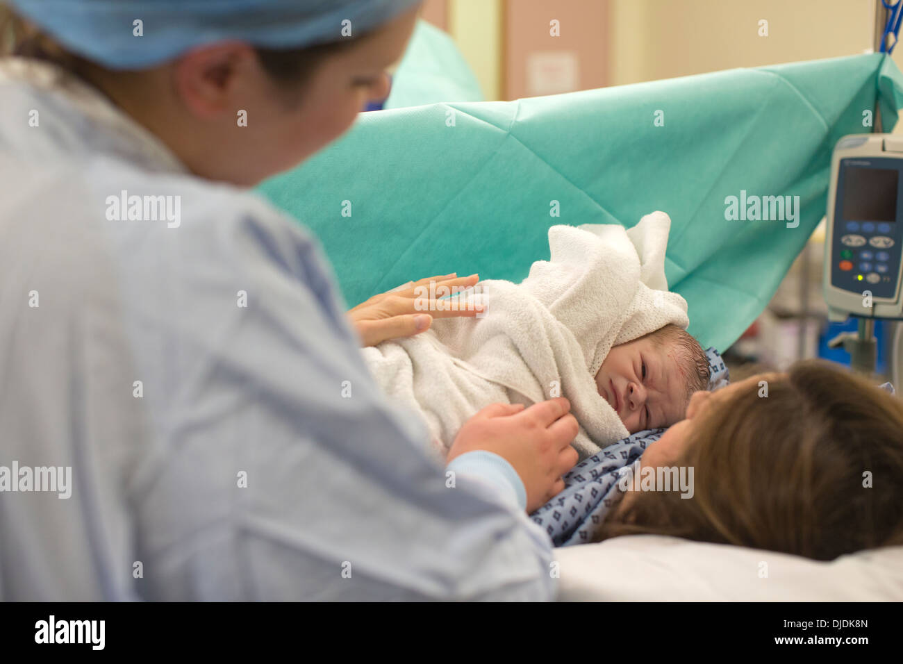 Newborn baby boy being checked by nurses in hospital maternity theatre on the Labour Ward at hospital, Kingston Upon Thames, UK Stock Photo