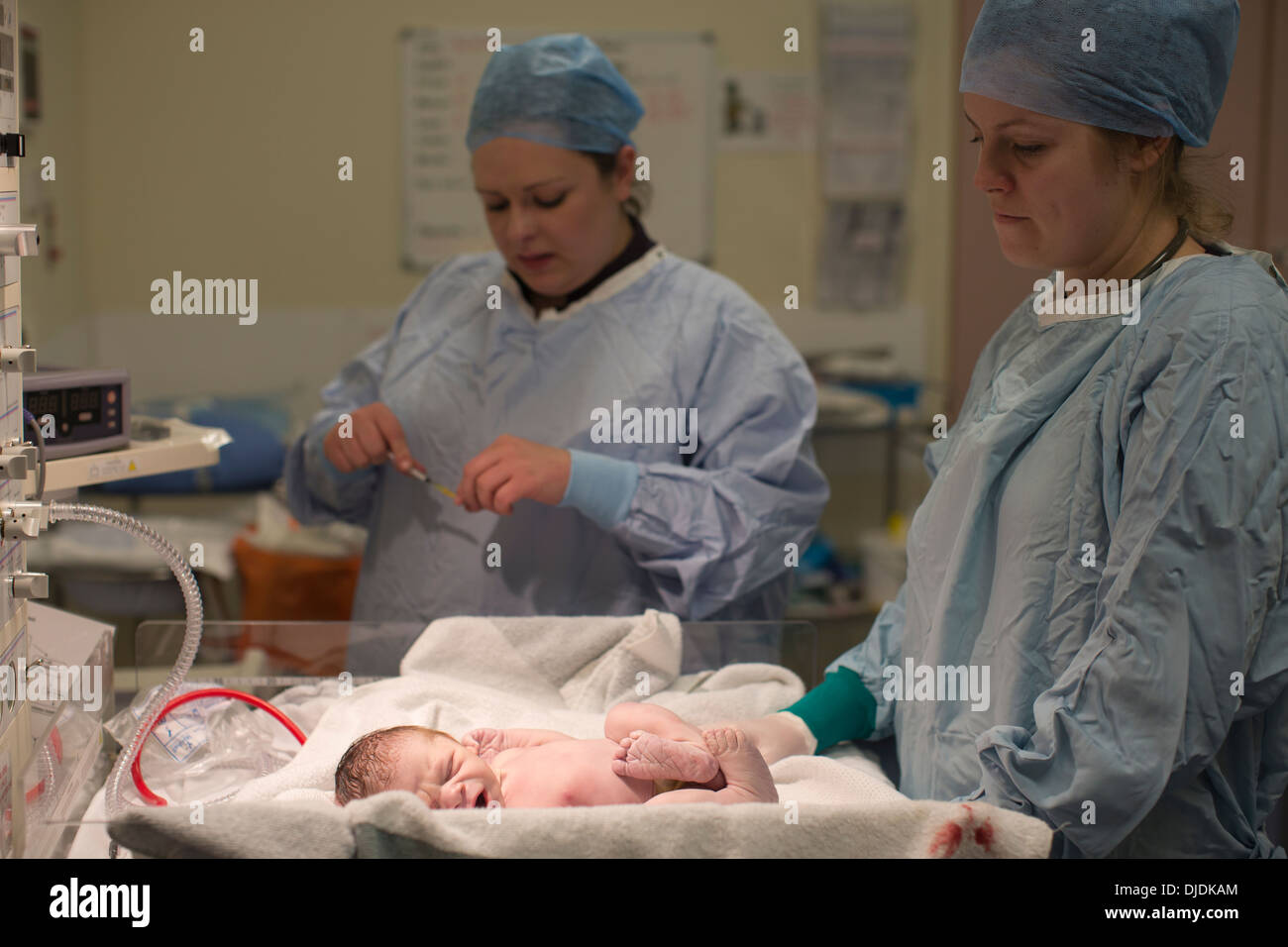 Newborn baby boy being checked by nurses in hospital maternity theatre on the Labour Ward at hospital, Kingston Upon Thames, UK Stock Photo