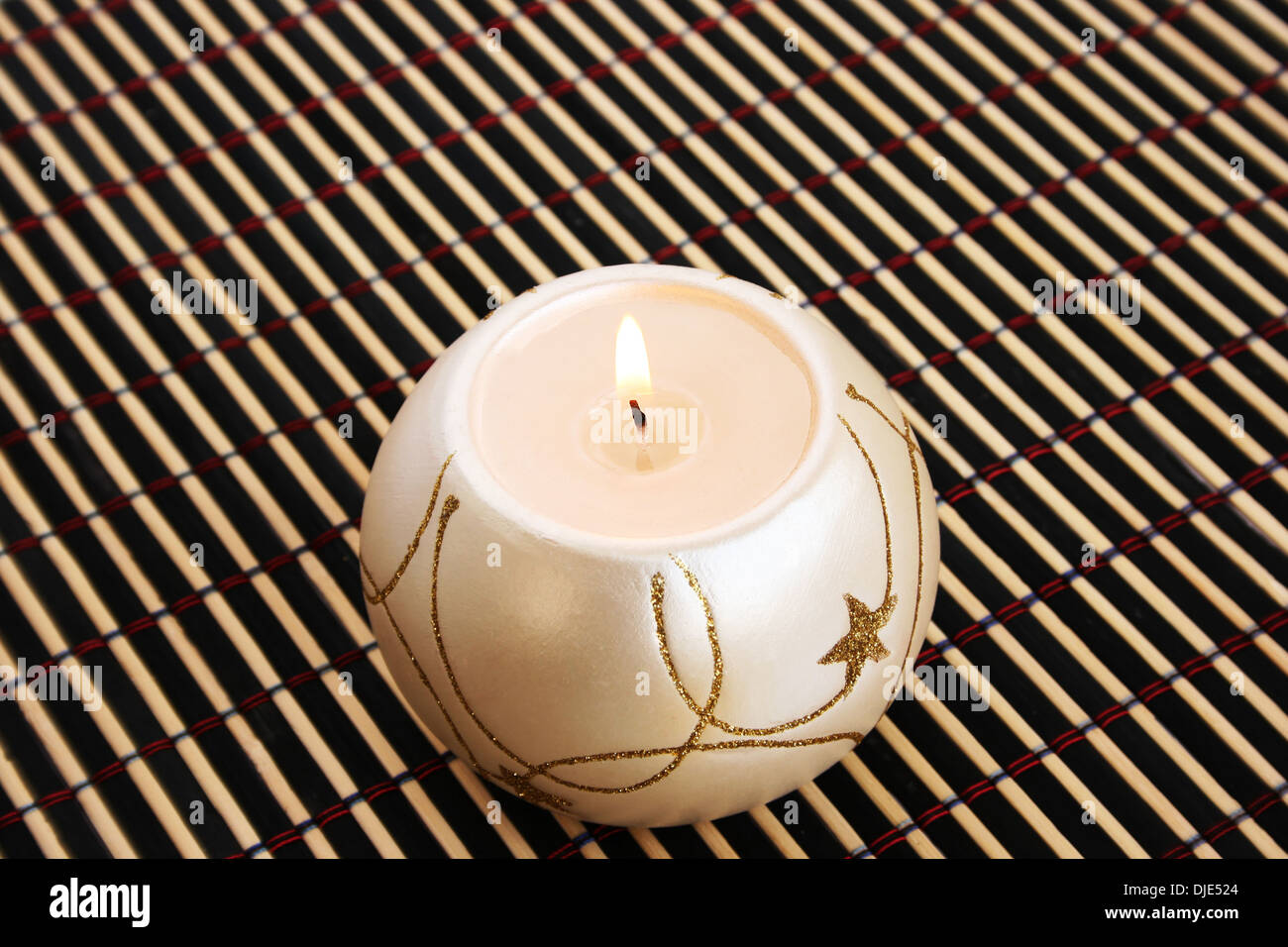 Burning candle isolated on bamboo background. Stock Photo