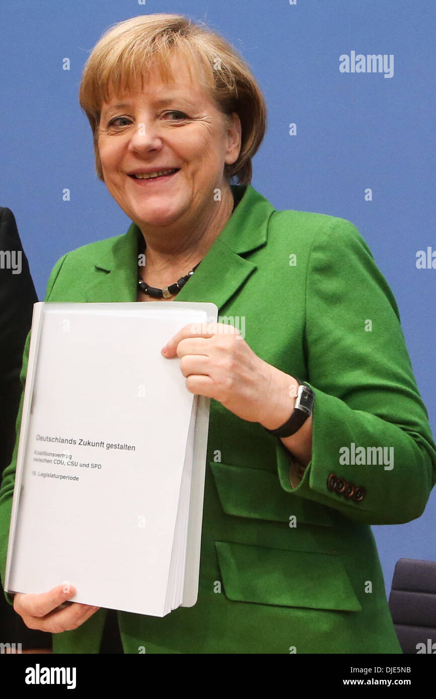 Berlin, Germany. 27th Nov, 2013. German Chancellor Angela Merkel displays the coalition agreement during a press conference in Berlin, Germany, on Nov. 27, 2013. Leaders from Germany's main parties signed provisionally a coalition agreement on Wednesday, paving the road for forming a new government two months after a federal election. Credit:  Zhang Fan/Xinhua/Alamy Live News Stock Photo