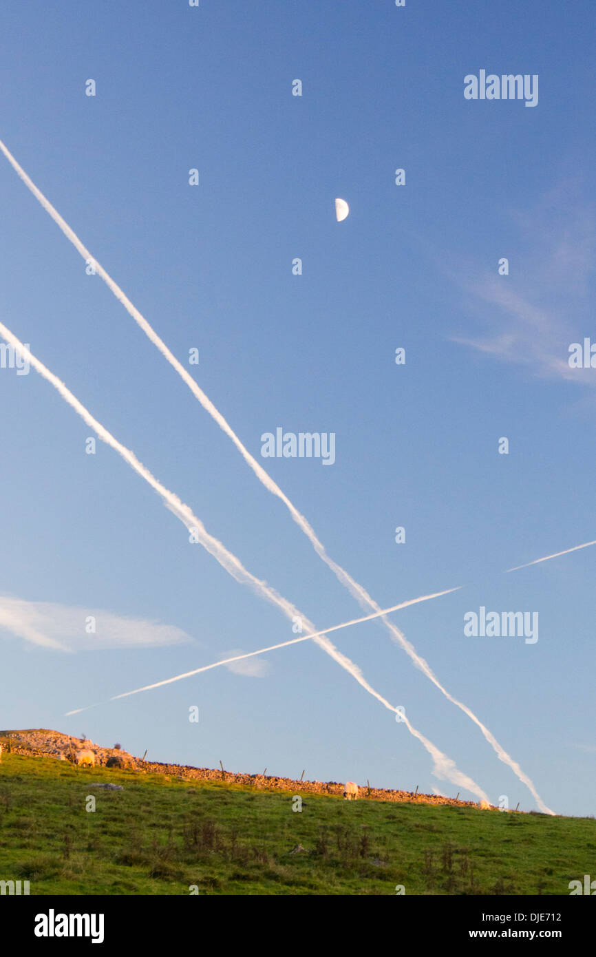 Contrails and a half moon over the Yorkshire Dales near Clapham, UK. Stock Photo