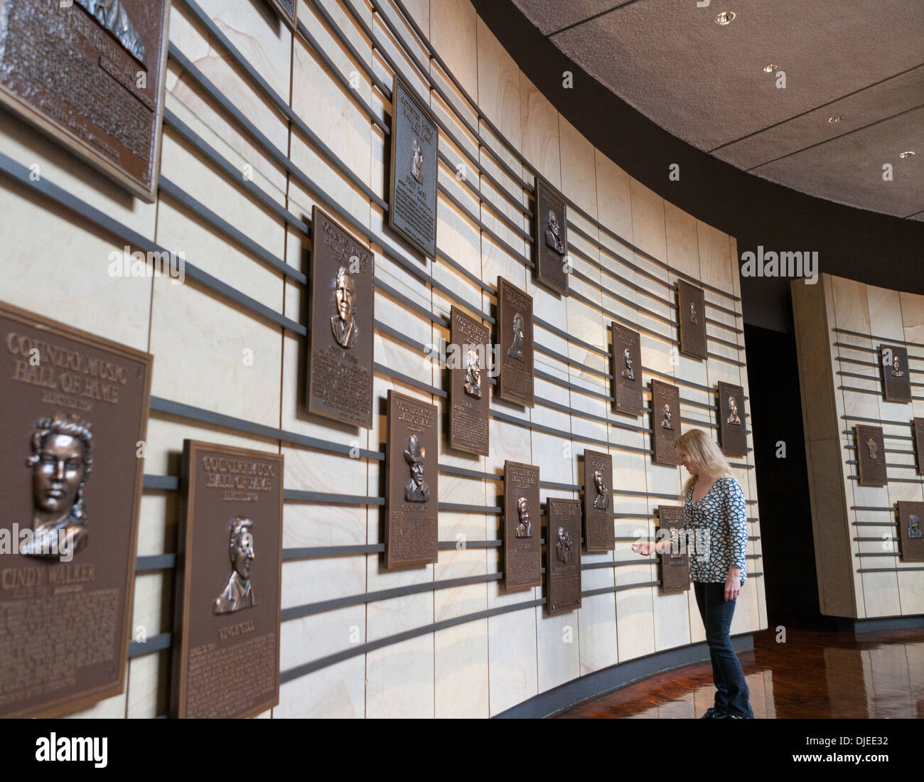 A woman looks at the plaques dedicated to country music stars on a wall inside the Country Music Hall of Fame in Nashville, TN. Stock Photo