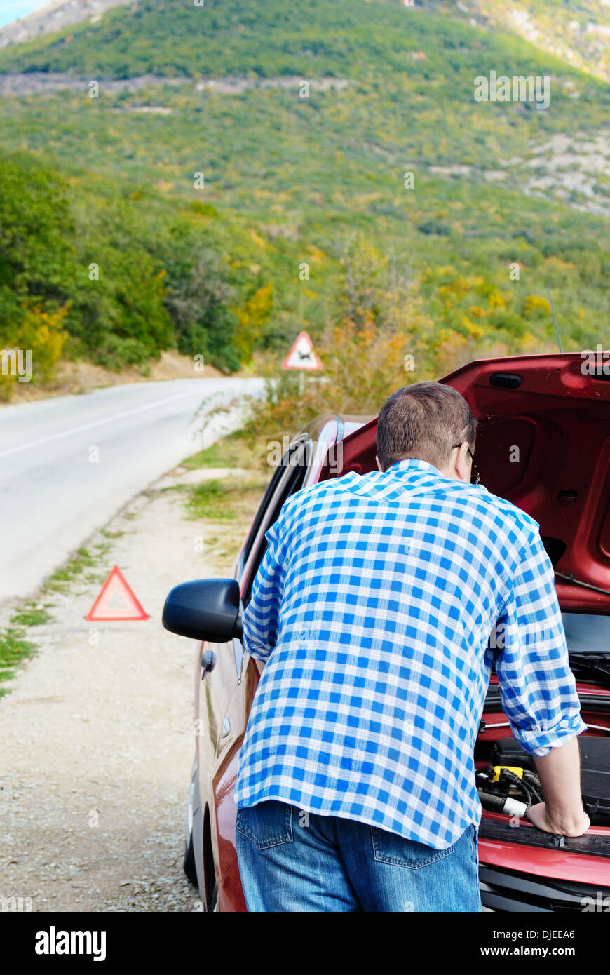 Adult man is standing near his broken car waiting for tow Stock Photo