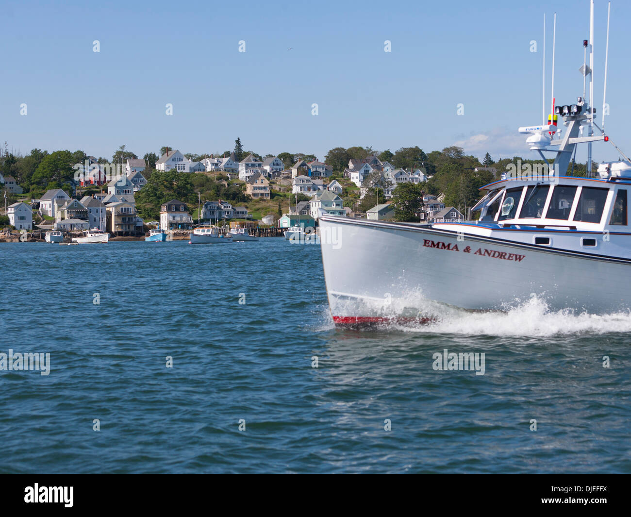 A lobster boat powers past the town of Stonington, ME. Stock Photo