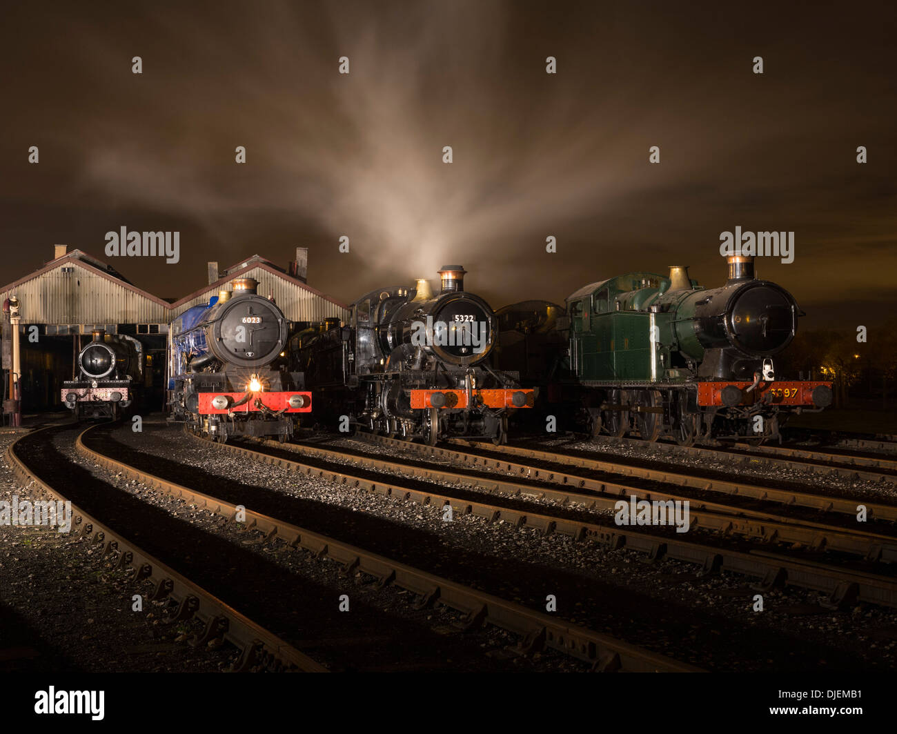 GWR  preserved steam locomotives 6023 'King Edward II', 43xx Class 2-6-0 5322 & Collett 5600 Class 0-6-2T 6697 on shed at night Stock Photo