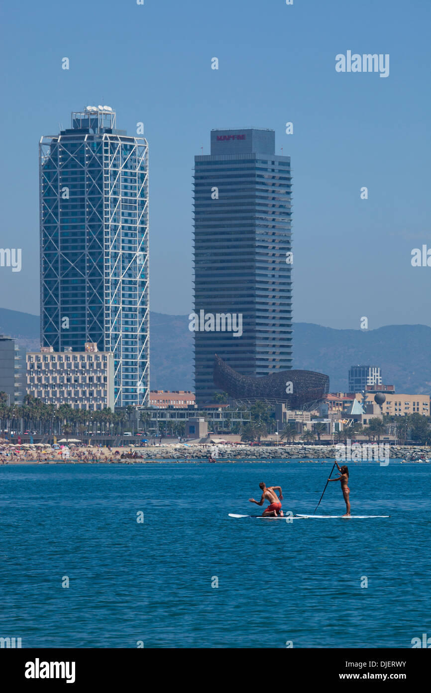 Two people doing SUP or stand up paddle boarding on Barcelona beach Stock Photo