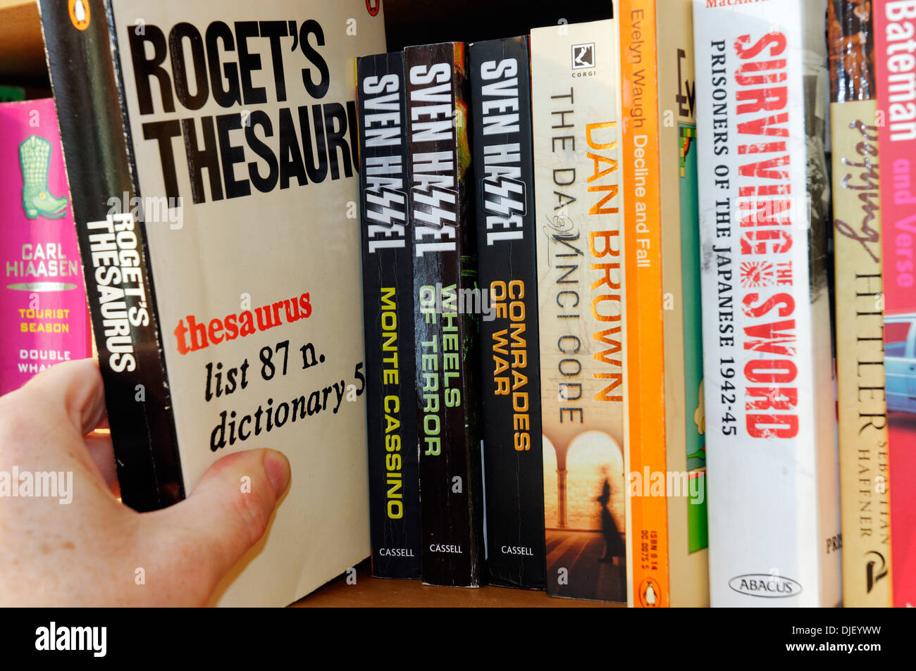 A hand taking Roget's Thesaurus from a bookshelf Stock Photo
