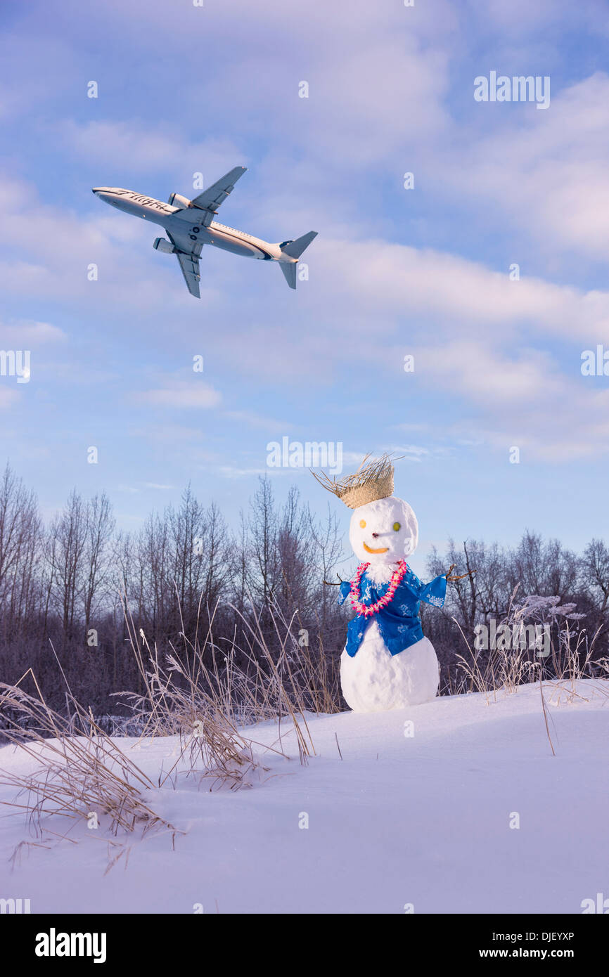 Composite: Alaska Airlines Jet In The Sky Above A Snowman Wearing An Hawaiian Outfit Ted Stevens International Airport Stock Photo