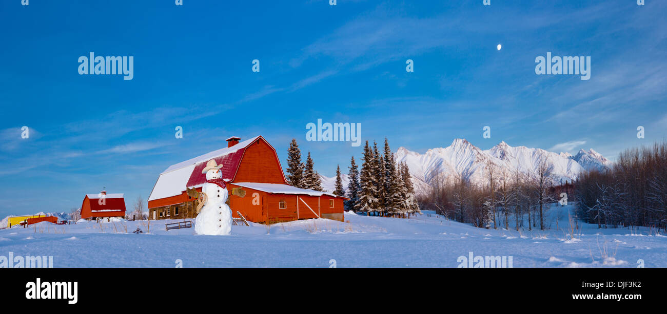 Snowman Dressed Up As A Cowboy Standing In Front Of A Vintage Red Barn, Palmer, Southcentral Alaska, Winter Stock Photo