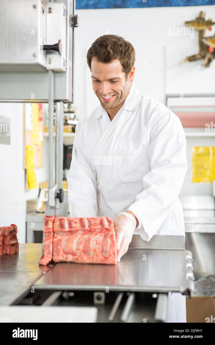 Butcher Slicing Meat On Bandsaw In Shop Stock Photo