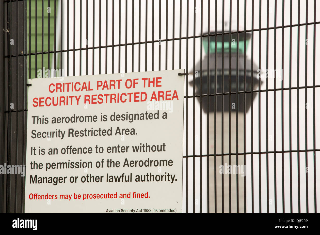 Signs on security fencing at Manchester Airport, UK, with the air traffic control tower behind. Stock Photo
