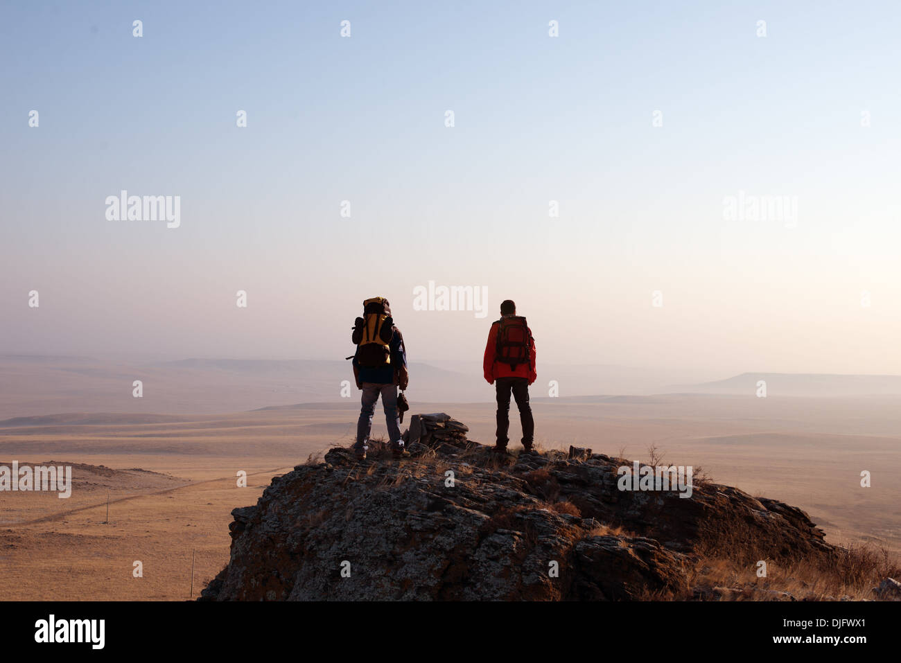 Two hikers enjoying sunrise from top of a mountain Stock Photo - Alamy