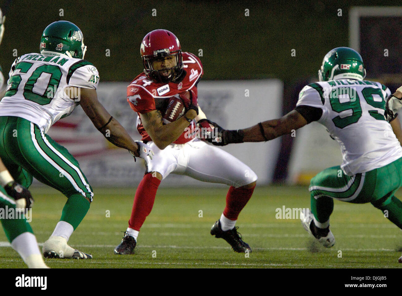 July 24, 2010 - Calgary, Alberta, Canada - 24 July 2010: Calgary Stampeders receiver Deon Murphy (24) attempts to get past Saskatchewan Roughriders linebacker Jerrell Freeman (50) and defensive end Shomari Williams (99) during a game against the Calgary Stampeders at McMahon Stadium in Calgary, Alberta.  The Calgary Stampeders defeated the Saskatchewan Roughriders 40 to 20..Mandato Stock Photo
