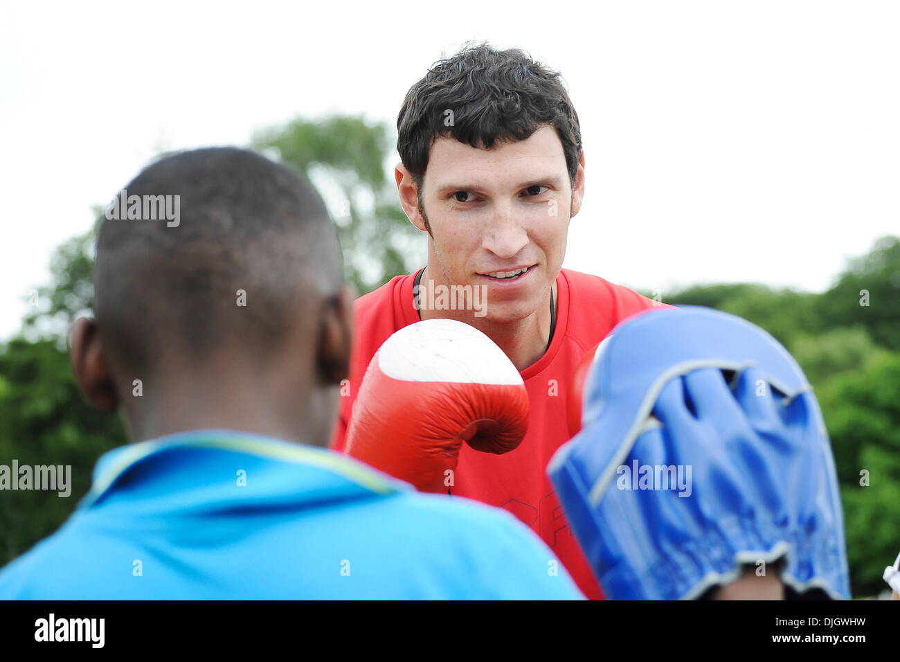 Lance Brooks (Discus) spars with students Olympic Team USA take part in a sports festival for city schoolchildren at Alexander Stadium, Perry Park. Birmingham, England - 07.19.12. Stock Photo