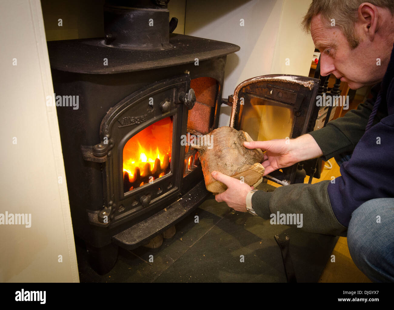 Man putting a log on a wood burning stove Stock Photo