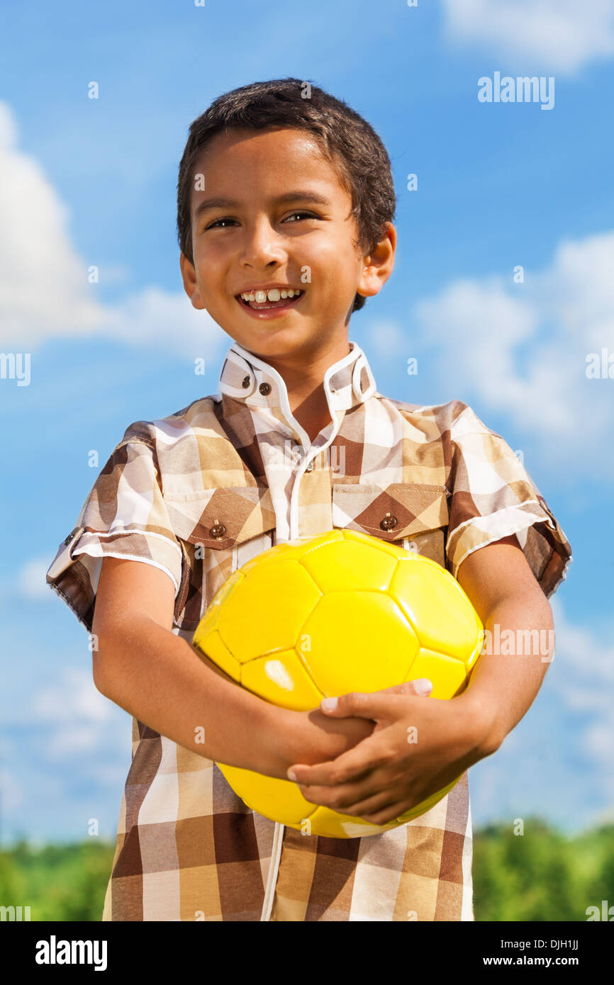 Portrait of happy dark boy standing with ball outside Stock Photo